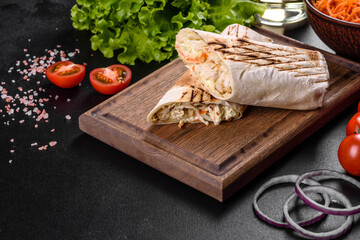 Delicious fresh shawarma with meat and vegetables on a dark concrete table