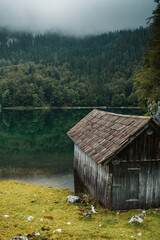 A wodden nature hut on a beautiufl mountain lake on a rainy moody spring day. Alps mountains, Austria
