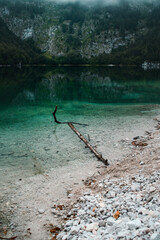 Crystal clear dark green montain lake with clear water on a moody dark rainy spring day. Alps mountains, Austria