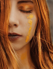 close up portrait of a woman with golden paint