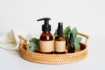 Set of eco natural organic cosmetics for personal hygiene in rattan tray. SPA beauty products design. Amber glass bottles mockups with labels.