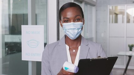 Businesswoman with face mask taking temperature at office entrance - Powered by Adobe