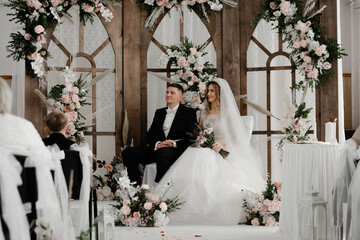 the groom and the bride are sitting at the wedding ceremony. newlyweds on the background of the...