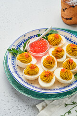 Stuffed eggs with red caviar and paprika on plate for appetizer easter table, top view, copy space. Traditional dish for Happy Easter holiday.