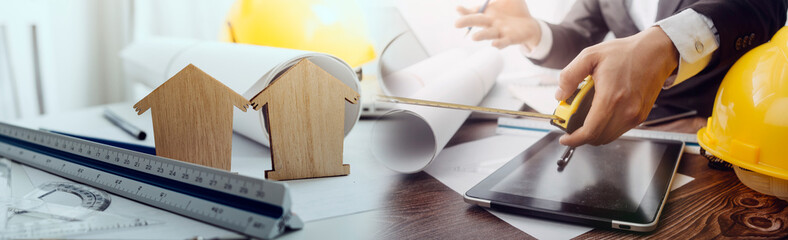 Two colleagues discussing data working and tablet, laptop with on on architectural project at construction site at desk in office