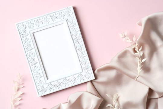 Stylish photo frame mockup, silk, flowers on pink background. Flat lay, top view, copy space.