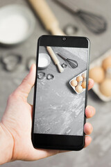 Female Hand with phone taking story with kitchen utensils for blog. Cook blogger filming video. Confectioner influence