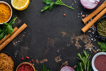 Set of Indian fragrant spices and herbs on a black stone background. Turmeric, dill, paprika, cinnamon, saffron, basil and rosemary in a spoon. Top view. Mock up.