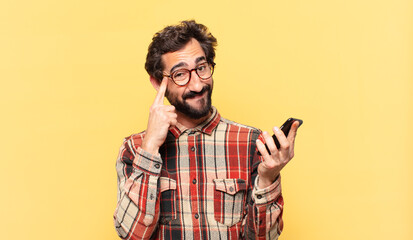 young crazy bearded man thinking expression and holding a phone - obrazy, fototapety, plakaty