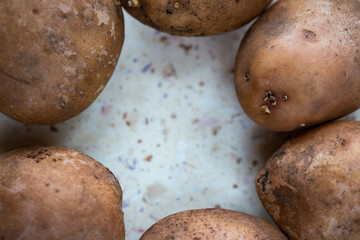 A few organic potatoes on the table. Made in natural light, soft shadows.