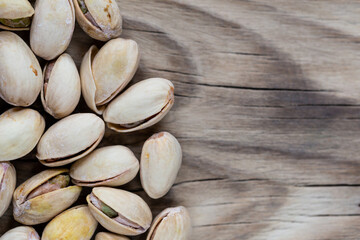 Lots of pistachios in their shell on a wooden chopping board. Natural, soft light