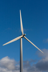 Single wind turbine rotors after a storm with a blue sky and clouds in the background
