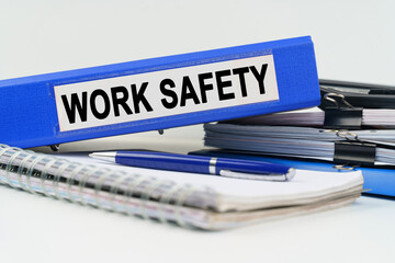 On the table are a notebook, a pen, documents and a folder with the inscription - WORK SAFETY