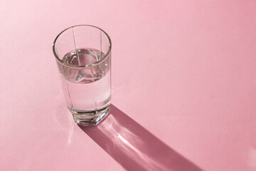 Glass of water on a pink background. Clean drinking water. Environmentally friendly water
