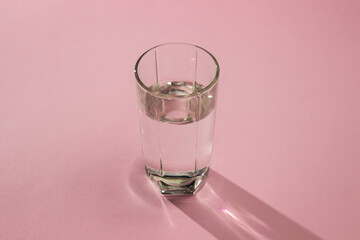 Glass of water on a pink background. Clean drinking water. Environmentally friendly water