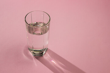 Glass of water on a pink background. Clean drinking water. Environmentally friendly water