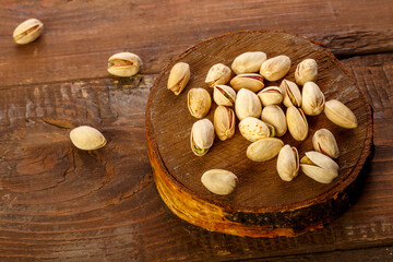 Fototapeta na wymiar Pistachio nuts scattered on a round board on a wooden table.