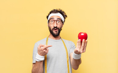 young crazy bearded athlete surprised expression and holding an apple and holding an apple