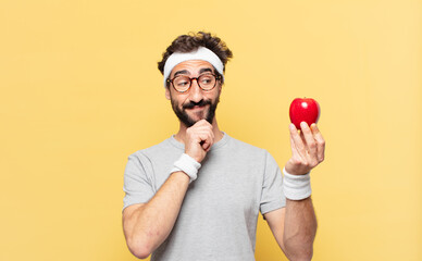 young crazy bearded athlete thinking expression and holding an apple and holding an apple