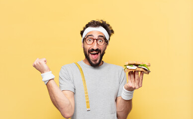 young crazy bearded athlete celebrating successful a victory and holding a sandwich