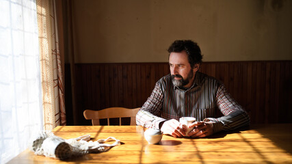 Portrait of unhappy poor mature man reading newspapers indoors at home, poverty concept.