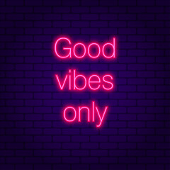 Good vibes only. Glowing pink neon incription on dark brick wall background.