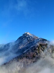Scenic view of Storzic mountain in Kamnik-Savinja alps, Gorenjska, Slovenia with mist covering the slopes and trees in the forest covered in frost