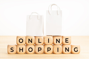 Online shopping concept. Text on wooden blocks on table and paper shopping bags. White background. Copy space