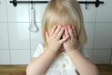 small child, baby, blonde girl covered her face with her palms from insult, crying, parenting...