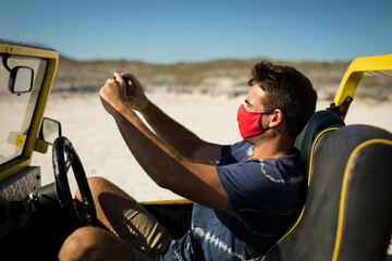 Caucasian man wearing face mask sitting in beach buggy taking picture