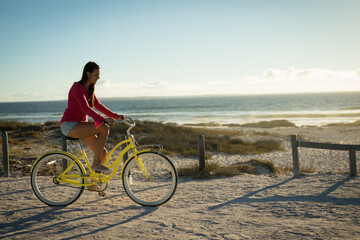 Fototapeta premium Happy caucasian woman on the beach riding bicycle