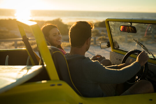 Happy caucasian couple sitting in beach buggy by the sea during sunset - Powered by Adobe