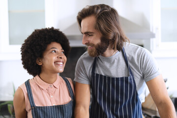 Obraz premium Happy diverse couple in kitchen embracing and smiling