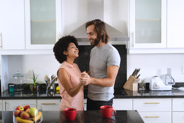 Happy diverse couple dancing in kitchen and smiling