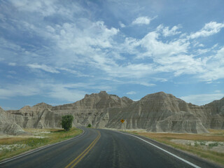 Fototapeta premium A road going through the surreal landscape and terrain at Badlands National Park in South Dakota