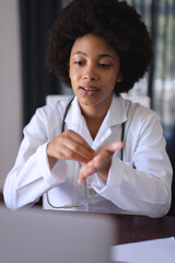 African american female doctor sitting making video call consultation