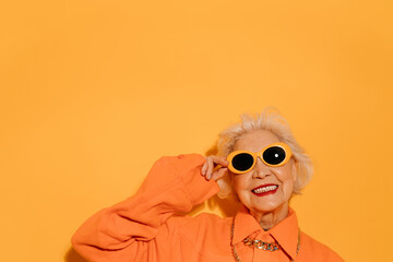 Woman smiling to the camera ​and holding hand at her sunglasses