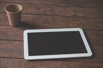 Modern office workspace with tablet pc on the table and a disposable cup of coffee.