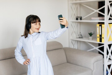 Teen girl at home dancing with headphones in her room with phone