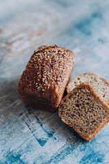 A loaf of brown bread with flax and sesame seeds on the table with the blue background