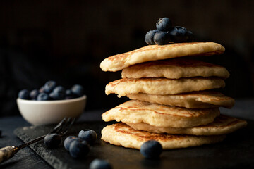 Stack of blueberry pancakes with syrup and fresh blueberries