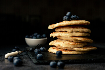 Stack of blueberry pancakes with syrup and fresh blueberries