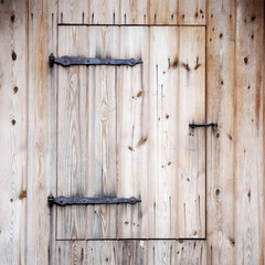New wooden door under the roof of an old barn with antique hinges