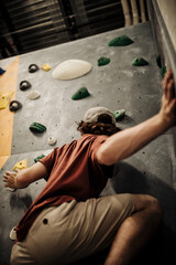 a young man climbing in indoor climbing place in the united states