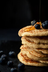Stack of blueberry pancakes with syrup and fresh blueberries
