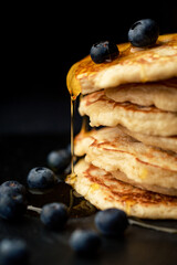 Stack of blueberry pancakes with syrup and fresh blueberries