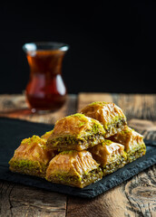 BAKLAVA. Traditional Turkish Desserts Baklava with Turkish Tea. Crispy pistachio baklava on black plate.