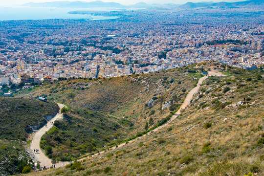 Drone view of the city of Athens in Greece. View from Ymittos mountain where people walking on a path in the mountain 