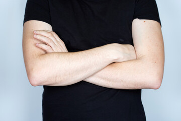 Man in a black t-shirt with crossed hands looking at the camera.