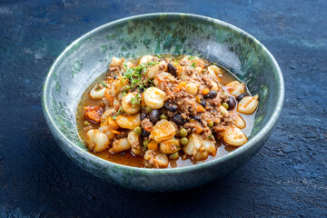 Modern style traditional slow cooked Mexican pozole rojo soup with ground minced beef, hominy maiz and beans served as close-up in a Nordic design plate